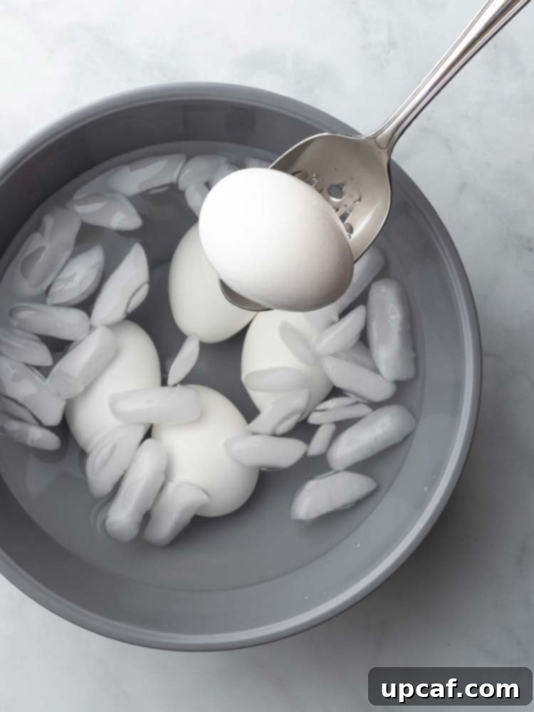 A peeled egg being removed from the ice bath, ready for consumption.