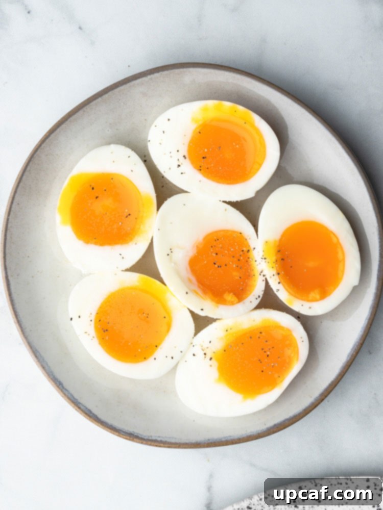 Two soft-boiled eggs, perfectly halved, showcasing their appealing runny yolks on a pristine white plate, garnished with fresh herbs for a refined presentation.