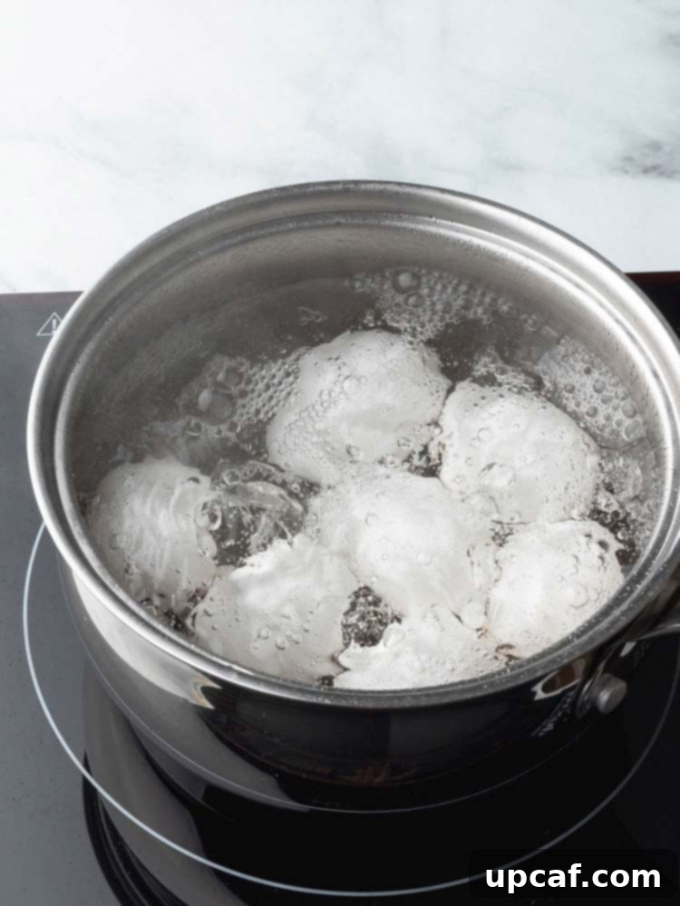 Fresh eggs gently simmering in a pot of water on the stovetop, demonstrating the first cooking phase for soft-boiled eggs.
