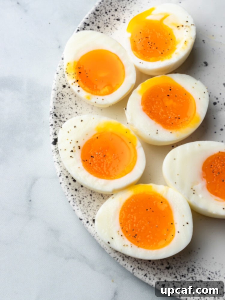 A close-up of a perfectly soft-boiled egg, halved to reveal its irresistible creamy and runny yolk, garnished subtly for serving.