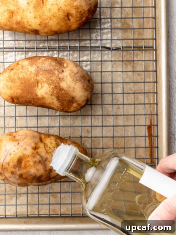 olive oil being drizzled on a potato before baking
