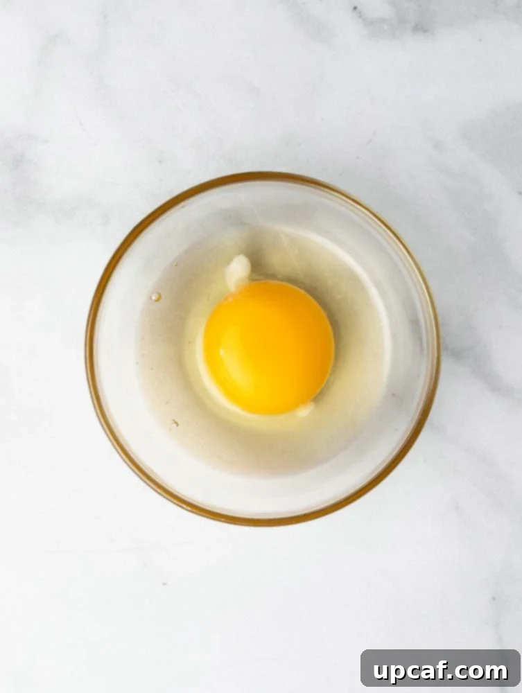 A cracked egg in a mesh sieve, straining off liquid whites