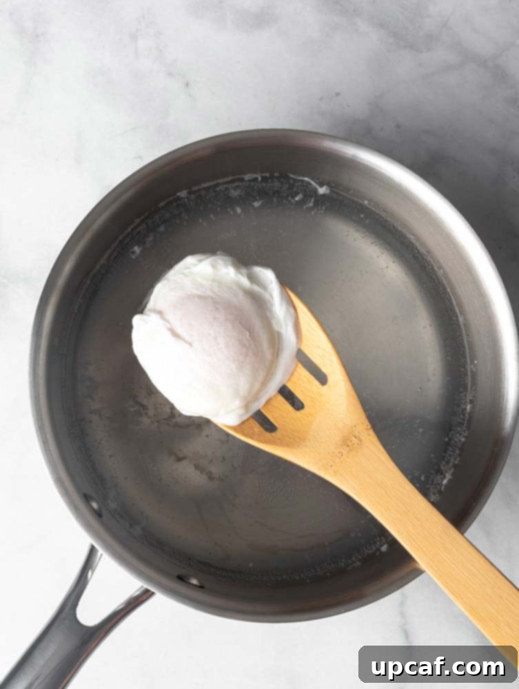Perfectly poached egg on a wooden slotted spoon