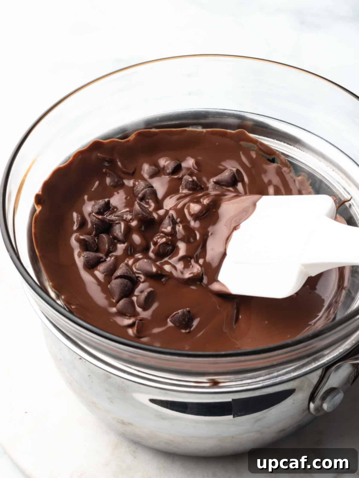 Chocolate chip pieces beginning to melt in a double boiler set over simmering water.