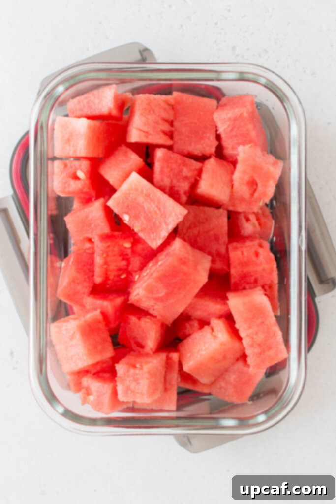 Freshly cut watermelon cubes stored neatly in a clear airtight container in the refrigerator.