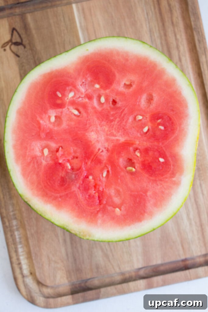 A watermelon cut cleanly in half, showcasing its vibrant red flesh.