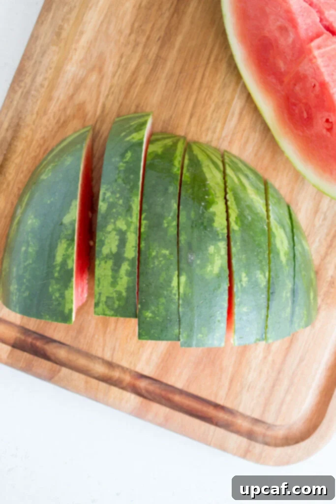 A quarter of watermelon being sliced into triangular wedges.